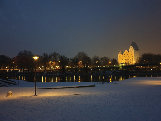 Winterlicher Abend am verschneiten Donauufer in Ingolstadt mit Blick auf das beleuchtete Schloss – stimmungsvolle Silvester Busreisen