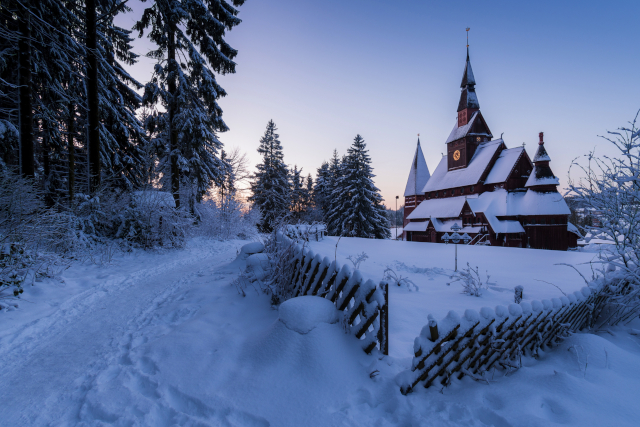 Verschneite Stabkirche in Hahnenklee im Harz im Abendlicht – winterliche Kulisse für besinnliche Adventsreisen mit dem Bus.