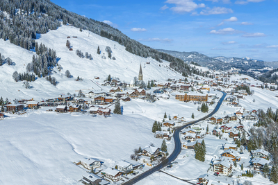 Luftaufnahme von Mittelberg im Kleinwalsertal mit verschneiten Berghängen und winterlichem Ortskern
