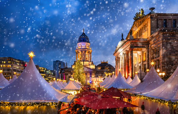 Weihnachtsmarkt am Gendarmenmarkt in Berlin bei Schneefall mit beleuchteten Kuppeln