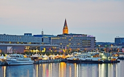 Hafen mit beleuchteten Schiffen und Gebäuden bei Sonnenuntergang.