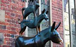Skulptur der Bremer Stadtmusikanten vor einem Backsteingebäude.