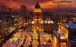 Weihnachtsmarkt in einer beleuchteten Stadt bei Sonnenuntergang.