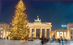 Weihnachtsbaum vor beleuchtetem Brandenburger Tor bei Nacht.