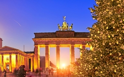 Brandenburger Tor bei Sonnenuntergang mit Weihnachtsbaum im Vordergrund.