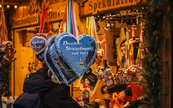 Menschen kaufen Lebkuchenherzen an einem Weihnachtsmarktstand.