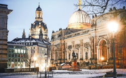 Verschneite Stadtansicht von Dresden mit historischer Architektur bei Abenddämmerung.