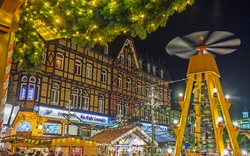 Weihnachtsmarkt bei Nacht, Fachwerkhaus, Lichter, Holzpyramide, festliche Atmosphäre.