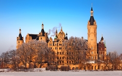 Schloss im Winter mit frostbedeckten Bäumen und klarem Himmel.
