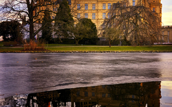 Schloss am See im Winter mit Spiegelung im Wasser.