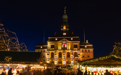 Weihnachtsmarkt vor dem beleuchteten historischen Rathaus in Lüneburg während des Winters.
