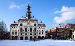 Historisches Gebäude auf verschneitem Platz bei blauem Himmel.