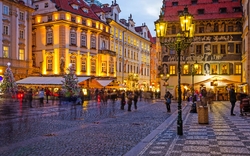 Eine belebte abendliche Stadtstraße mit beleuchteten Gebäuden und Weihnachtsdekoration.