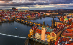 Blick auf die Karlsbrücke und die Stadt Prag bei bewölktem Himmel.