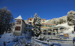 Ein verschneites Berghotel mit klarblauem Himmel im Hintergrund.