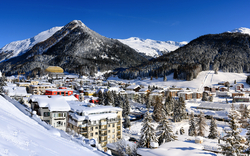 Schneebedecktes Bergdorf mit Häusern und Wald im Winter.