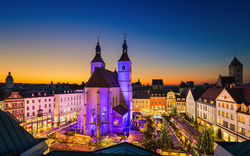 Abendstimmung über einem festlich beleuchteten Weihnachtsmarkt in einer historischen Altstadt.