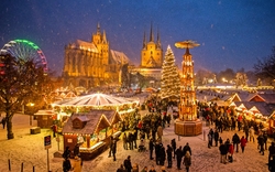 Verschneiter Weihnachtsmarkt mit Lichtern und Menschen in festlicher Stimmung.