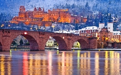 Alte Brücke und Schloss Heidelberg im Winter bei Dämmerung reflektieren im Neckar.