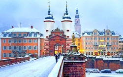 Schneebedeckte Brücke und mittelalterliches Tor in einer deutschen Stadt im Winter.