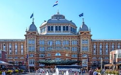 Historisches Hotelgebäude mit Flaggen und Menschen davor.