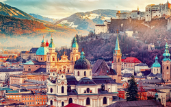 Stadtansicht mit historischen Gebäuden und Burg auf Hügel in Salzburg bei Sonnenuntergang