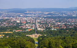 Blick auf Kassel mit grünem Park und umliegenden Hügeln.