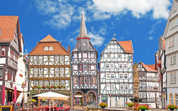 Fachwerkhäuser an einem historischen Marktplatz unter blauem Himmel.