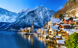 Hallstatt im Winter mit schneebedeckten Alpen im Hintergrund, am Ufer des Hallstätter Sees.