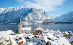 Verschneite Stadt mit Kirche vor winterlichem Bergsee.