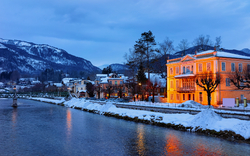 Winterliche Flusslandschaft mit beleuchtetem Gebäude.