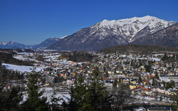 Blick auf eine verschneite Stadt mit Bergen im Hintergrund bei klarem Himmel.