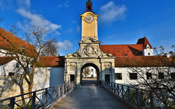 Historisches Stadttor mit Turmuhr an einem sonnigen Tag.