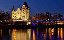 Neues Schloss Ingolstadt bei Abenddämmerung, beleuchtet, im Winter mit Blick auf die Donau.