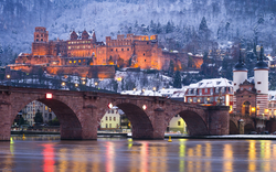 Heidelberger Schloss bei Nacht mit beleuchteter Alter Brücke im Winter.