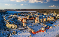 Kurhaus von Binz im Winter, umgeben von schneebedeckten Gebäuden und der gefrorenen Ostsee.