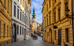 Leere Straße in Altstadt mit historischer Architektur und Turm im Hintergrund