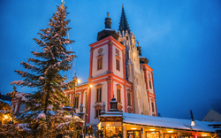Kirche im Schnee bei Abenddämmerung, dekoriert mit Lichtern.