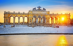 Barockes Bauwerk im Schnee bei Sonnenuntergang, mit Menschen im Vordergrund.