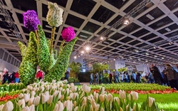 Blumenskulpturen und Besucher in einer großen Ausstellungshalle.
