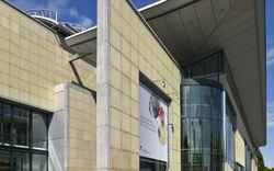 Moderner Haupteingang eines Museums mit Glasfassade und großem Vordach.