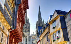 Fachwerkhäuser vor einer Kathedrale mit hohen Türmen bei Tageslicht.