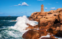 Leuchtturm auf Klippen, Wellen schlagen gegen Felsen im Meer.