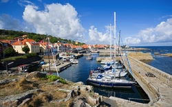 Hafen mit Segelbooten und bunten Gebäuden unter blauem Himmel.