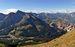 Blick auf Gebirgslandschaft mit einem Tagebau in sonniger Umgebung.