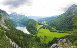 Berglandschaft mit Tal, See und grünem Wald.