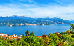 Panorama eines Sees mit Bergen und einer Stadt im Hintergrund bei klarem Wetter.