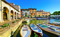 Boote im Hafen vor bunten historischen Gebäuden bei sonnigem Wetter.