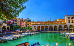 Hafen mit Booten, historischen Gebäuden und blauem Himmel im Hintergrund.