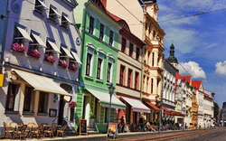 Straße mit bunten historischen Gebäuden und Außensitzbereichen bei sonnigem Wetter